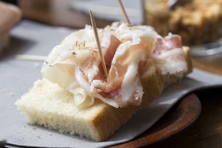 closeup of a slice of bread with a thin slice of pancetta on it の写真素材