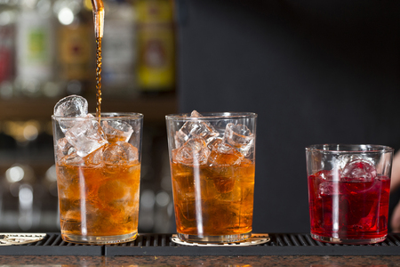 closeup of a barman making three colorful cocktails on a bar counterの写真素材