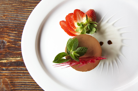 chocolate and strawberry mousse on a white plate and wooden backgroundの写真素材