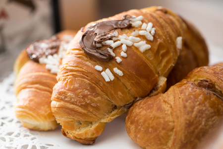 a golden croissant filled with chocolate cream and with some hazelnut cream on top on a bar counterの写真素材
