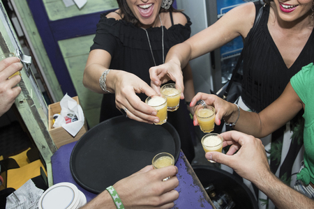 a closeup of a group of friends  celebrating with an alcoholic shot in a barの写真素材