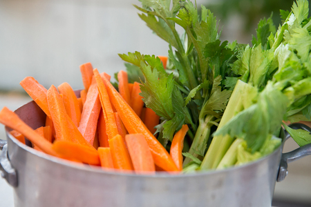 closeup of a party buffet, some fresh sliced cellery and carrots in a aluminum potの写真素材
