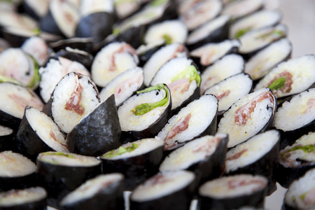 a closeup of a tray full of italian sushi made with rice, green salad, hamの写真素材