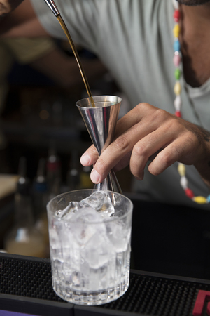 a closeup of a bartender measuring wisky with a Jiggerの写真素材