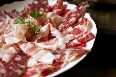 a plate of italian seasoned sliced meat with pancetta, salame and coppa all made in Piacenza, north Italy. subject on the left with dark backgroundの写真素材