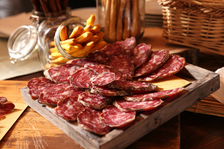 slices of italian salame on a buffet with bread sticks on the backgroundの写真素材