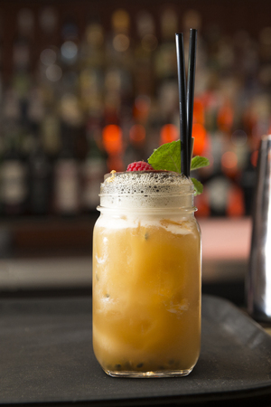 alcohol free refreshing cocktail with fresh fruit juice and raspberry on top, the glass is on a bar counterの写真素材