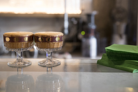 two cold shakared coffee on a bar counter, glasses are elegant and vintage glasses. Subject and focus on the leftの写真素材