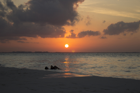 a woman lying in the caribean red sunset の写真素材