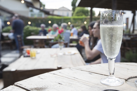 closeup of a white wooden table with a glass of cold prosecco on it. の写真素材