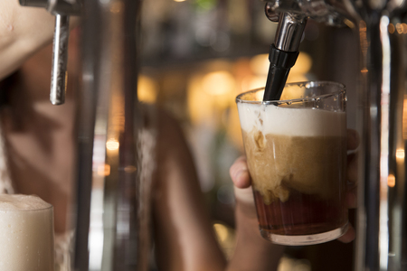 closeup of a bartender pouring a dark red beer in tap with subject and focus on the rightの写真素材