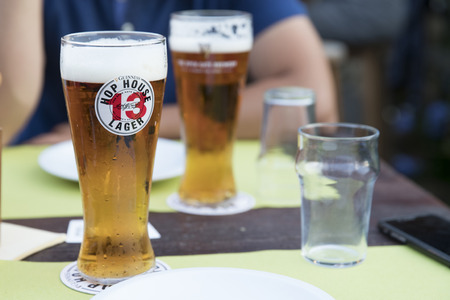 PIACENZA, ITALY - JUNE 15, 2018: horizontal closeup of a glass of Guinness Hop House 13 Lager on a restaurant table, subject and focus on the left.のeditorial素材