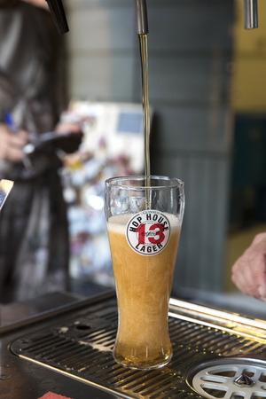 PIACENZA, ITALY - JUNE 15, 2018: vertical shot of a glass of Guinness Hop House 13 Lager under a beer tapのeditorial素材