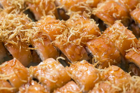 closeup of a tray of salmon uramaki filled with salmon and fresh cream cheese and garnished with fried onionsの写真素材