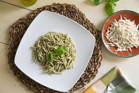 flat shot of a plate of italian trofie with pesto on a white wooden tableの写真素材