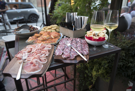 closeup of bar table with two cold glasses of white wine next to an outdoor food buffet during a partyの写真素材