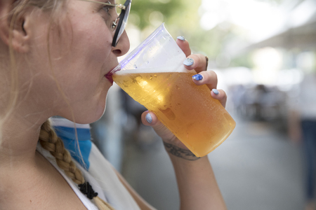 close up of a young blonde girl drinking beer in a plastic glass