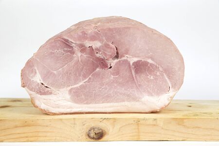 a whole italian cooked  ham on a wood chopboard on white backgroundの写真素材