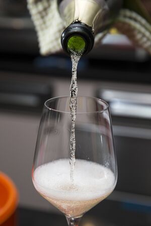 vertical closeup of a barman pouring prosecco into a glass behind the bar counterの写真素材