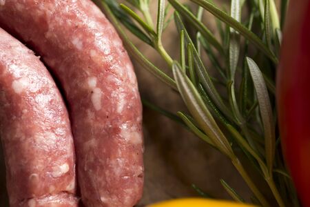 horizontal closeup of italian sausages next to some rosemaryの写真素材