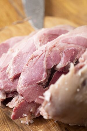 vertical closeup of a typical italian food of Emilia Romagna on a olive wooden chop board: cappello del prete (Priest's Hat) , seasoned pork meat, boiled and sliced. subject and focus on the rightの写真素材