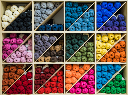 brightly colored skeins of wool organized by color on shelves