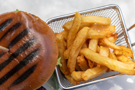 Delicious burger on a bun and fries in a basket.の写真素材