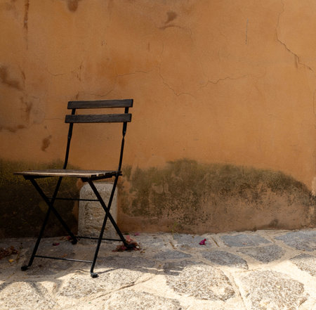 Folding chair near an old wall in a narrow old street.の写真素材