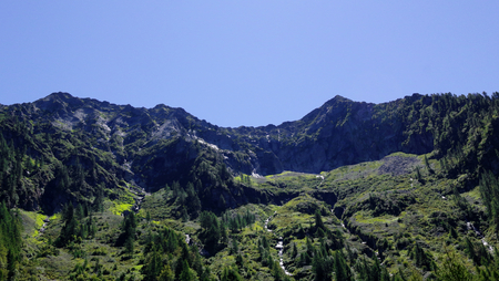 A landscape of green mountains, with pines and firs, rocks and glaciers, in the Vigezzo Valley, northern Italian Alpsの写真素材