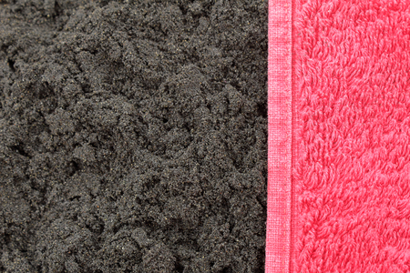 The hem of a red terry towel onto the black sand of Almaciga playa in Tenerife, Canary islandsの写真素材