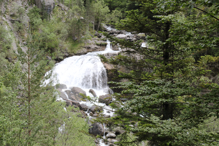 A rural landscape with Araza River waterfalls in the the pines and firs forest, with the Monte Perdido mountains on the background, in the Ordesa protected natural park in Aragon, Spainの写真素材