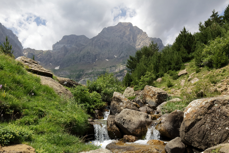The Piedrafita de Jaca lake and Barranco Cuasta river with the Pena Telera massif in the aragonese Pyrenees mountainsの写真素材