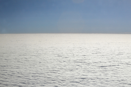 An areal view of flat uniform homogeneous clouds and a deep blue sky as as seen from an airplaneの写真素材