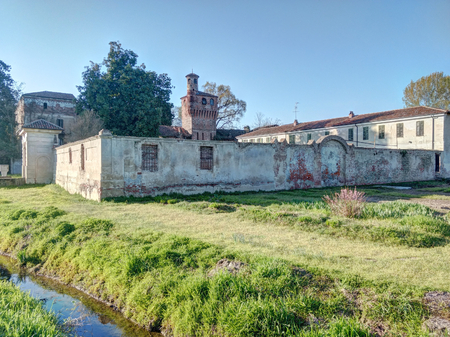The old cotto bricks made abandoned castle of Albano Vercellese, Piedmont region, Italy, next to a green lawn and an artificial canalのeditorial素材