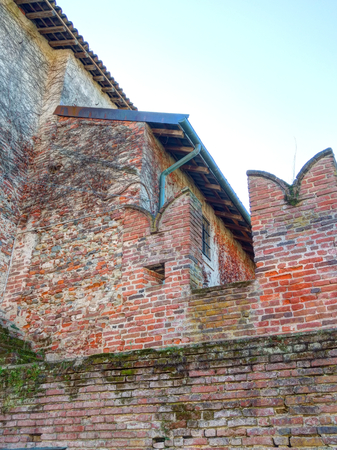 Two cotto brick Ghibelline merlons with some moss and moisture in a sunny day in the Saints Nazarius and Celsus abbey, Piedmont, Italyのeditorial素材