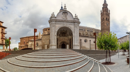 The Nuestra Senora de la Huerta gothic and mudejar cathedral facade and bell tower, seen from the entrance staircase in perspective, in a cloudy, autumn day in Tarrazona, Aragon, Spainの写真素材