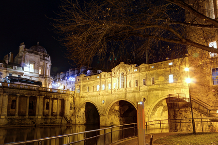 The Pultney bridge reflecting into the Avon river next to a park in winter, with night lights, in Bath, Somerset region, United Kingdomのeditorial素材