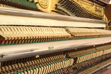 A close view of the mechanic of an upright piano, with tuning hitch pins, hammer heads, the vibrating strings and the soft mute (sordino) felt clothのeditorial素材