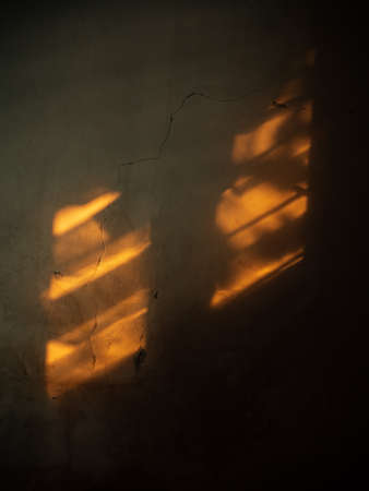 The afternoon sun shines on the textured walls in the dark room of house.の写真素材