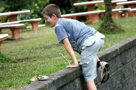 Boy climbing a wall of stonesの写真素材