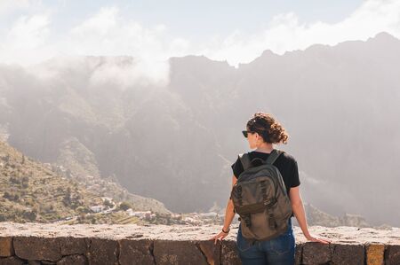 woman from behind with backpack looking at landscapeの写真素材