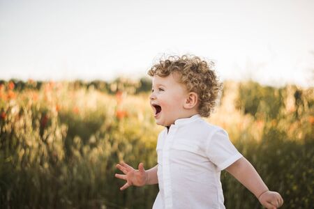 blond baby running the summer road and fieldの写真素材