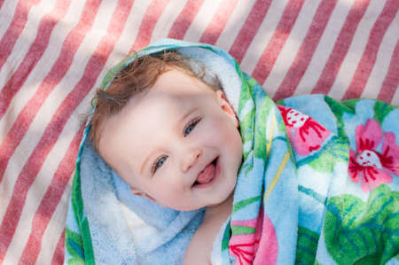 Smiling blond baby with blue eyes sticking out his tongueの写真素材
