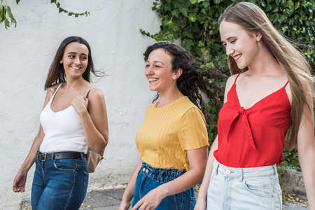 Three happy young tourist friends back to back looking at a village landscape