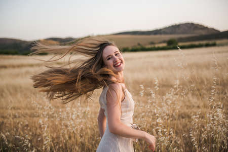 a young woman moving her long blonde hair in a country backgroundの写真素材