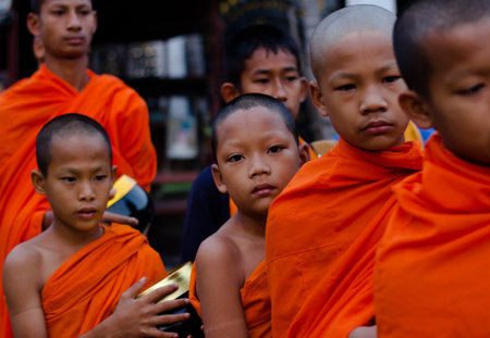 Kanchanaburi, Thailand - March 16, 2014: Young monks waiting for receive food from villagers in Sangkhlaburi, Thailandのeditorial素材