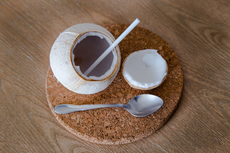 Fresh coconut with straw and spoon on the tableの写真素材