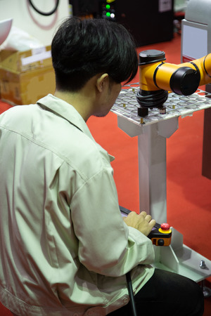 Worker control robot arm to loading and unloading workpieceの写真素材