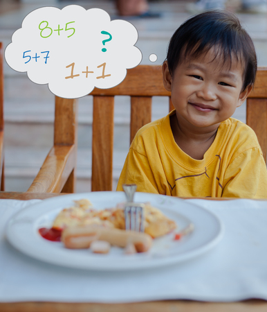 Asian boy calculate mathematic during eat breakfastの写真素材