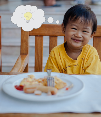 Asian boy has an idea during eat breakfastの写真素材